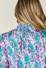 A woman wears a double take full size printed smocked long sleeve blouse with turquoise and purple paisley pattern