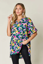 A vibrant double take full size printed v-neck short sleeve side slit top with bold abstract floral print in pink yellow green and purple on lightweight fabric ideal for jeans size