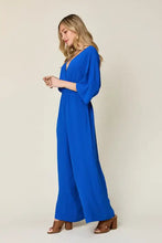 Vibrant royal blue surplice wide leg jumpsuit with deep V-neck and pockets