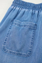 Blue denim drawstring elastic waist pocketed loose fit shorts with visible stitching and front pocket detail