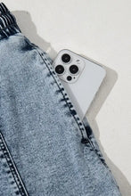 White iPhone 13 Pro in pocket of high waist pocketed denim skirt