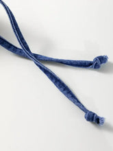 Blue denim drawstring with frayed ends and knots on a high waist denim mini dress with puff sleeves
