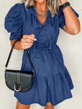 Black leather crossbody bag with gold-tone buckle and flap closure paired with a high waist denim mini dress