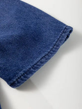 A close-up of dark blue high waist denim mini dress fabric with visible stitching along the folded edge