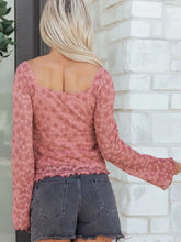 A soft pink floral lace blouse featuring a drawstring knot detail, long sleeves, square neckline, and ruffled hem