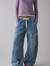 Wide-leg faded blue denim cargo jeans with a white drawstring waist featuring a comfortable drawstring waist cargo design