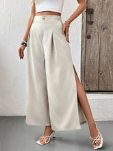Cream-colored slit wide leg pleated pants with high waist, front slit, and gold button closure