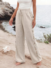 Beige linen drawstring wide leg pants with silver shell trim along side seams for a stylish wide leg look