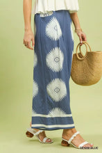 Denim blue maxi skirt with white sunburst patterns and matching striped hem featuring an abstract border print design
