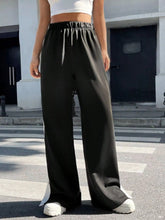 Black high-waisted snap wide leg pants with elastic waistband made of smooth flowing fabric