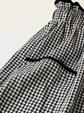 Black and white gingham pattern wide-leg pants with a ruffled waistband detail for a stylish look