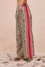 BiBi leopard print pants with wide-leg design and bold red and white vertical stripes down the side