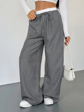Black and white striped wide leg drawstring pants featuring a comfortable waistband for casual wear