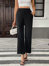 Black pearl-embellished cropped wide-leg pants with sleek flowing fabric and silver studs along the hem