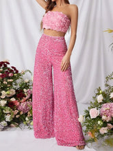 A vibrant pink sequin embellished wide leg pants set with a strapless top featuring rose appliqués and wide leg pants
