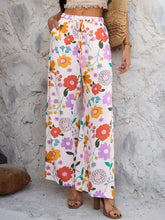 Devine drawstring pants featuring floral print wide-leg design with orange purple and pink blossoms on white background