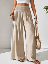 Beige smocked waist wide leg pants with elastic high waistband and two front pockets for comfortable wear