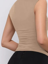 Beige sleeveless top with ruched back, machine wash cold, paired with black leggings