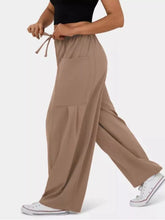 Beige drawstring wide leg pants with large front pocket designed for comfortable casual wear