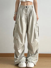 Beige cargo pants with wide legs, multiple large pockets, and a drawstring waistband in wide leg cargo style