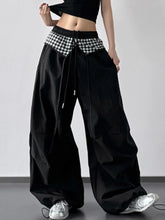 Black wide leg pants with a contrasting black and white checkered waistband and drawstring ties for comfortable wear