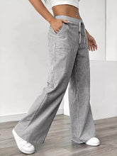 Striped wide leg pants in gray and white vertical stripes with a drawstring waistband for comfortable wear