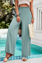 A pair of devine smocked wide leg pants in soft sage green fabric with elasticated waistband and pockets