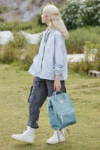 Person in blue jacket holding eco-friendly waterproof canvas backpack bag