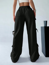 Black cargo wide leg pants with side pockets and adjustable drawstrings featuring side tie details
