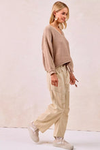 Beige ribbed knit sweater with long sleeves and v neckline paired with bi bi drawstring striped twill barrel pants