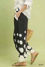 Black wide leg pants with bold white hexagon print and scalloped ruffled cuffs by Umgee