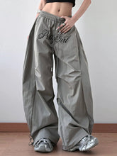 Gray drawstring oversized wide leg casual pants with pretty girl embroidered in black script on the thigh