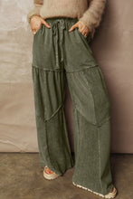 Olive green tiered wide leg pants featuring a layered patchwork design and drawstring waistband