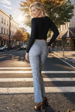 A woman wearing heimish plus size plaid flare pants with wide waistband paired with brown heeled boots and black top