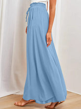 Light blue flowing wide leg pants with elastic waistband and drawstring featuring pockets for comfort and style