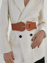 Woman in white blazer wearing elastic wide belt with gold O-ring buckle