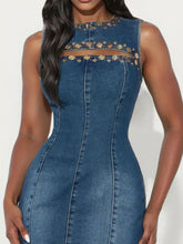 A fitted blue sleeveless denim dress with gold-tone studs and cutout details along the neckline