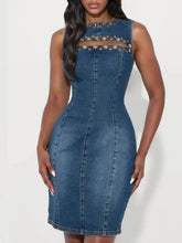 A fitted blue sleeveless denim dress with high neckline and gold embellishments on cutout shoulder areas