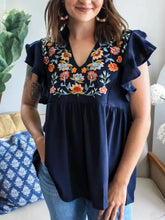 Navy blue embroidered floral ruffle sleeve blouse with v-neckline and delicate floral ruffle detailing on sleeves