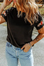Black short-sleeved embroidered round neck tee shirt with floral shoulder details