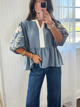 Light blue sleeve peplum blouse with white embroidered leaf details on sleeves and v-neckline for elegant wear