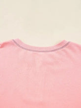 A soft pink ribbed crewneck top with subtle gradient and color block patchwork slit cuffs in an oversize sweatshirt style