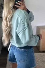 Light blue exposed seam cropped sweatshirt with dark navy ribbed cuffs made of slightly stretchy material machine wash cold