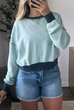Light blue exposed seam cropped sweatshirt with dark navy ribbed cuffs made of slightly stretchy material, machine wash cold