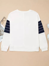 White sweatshirt with exposed seam detail and navy blue striped sleeve panels designed for machine wash cold care