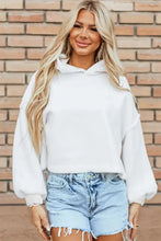 Woman in exposed seam long sleeve hoodie with denim shorts