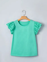 A mint green eyelet lace ruffled cap sleeve top hanging on a wooden hanger with delicate lace detailing