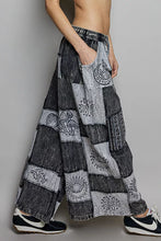 Black and gray patchwork wide leg pants with drawstring and embroidered tribal patterns in a patchwork wide leg design