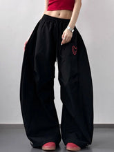 Black wide leg casual pants with red heart embroidery on the thigh featuring a comfortable wide leg casual fit
