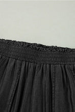 Black pleated skirt with elastic waistband featuring smocked high waist for a comfortable stylish fit